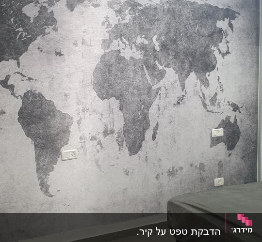 קיר בחדר שינה מחופה בטפט מעוצב בדוגמת מפת עולם אפורה